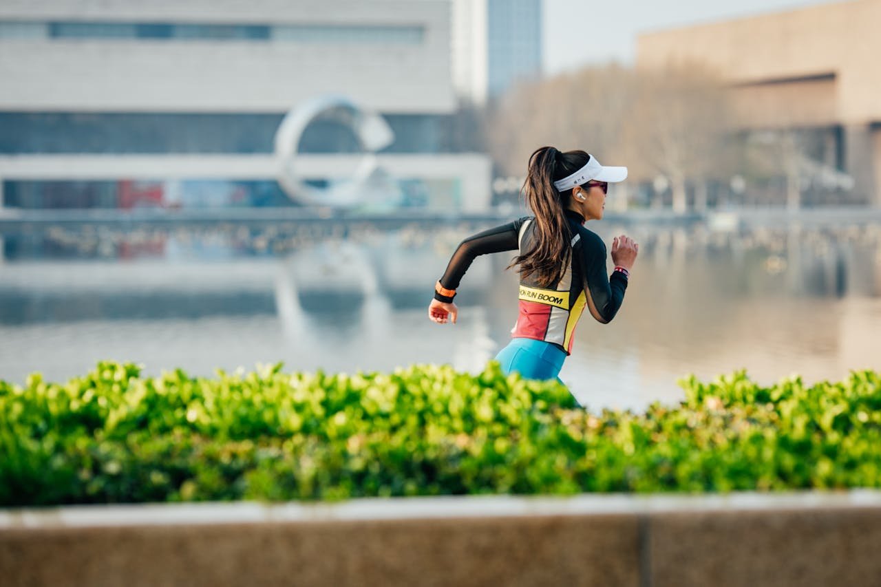 Services Woman running along an urban lakeside path, exercising with focus and determination amidst cityscape.