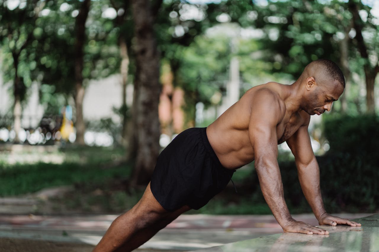 Home Athletic man performing push-ups outside, focusing on physical strength and endurance.
